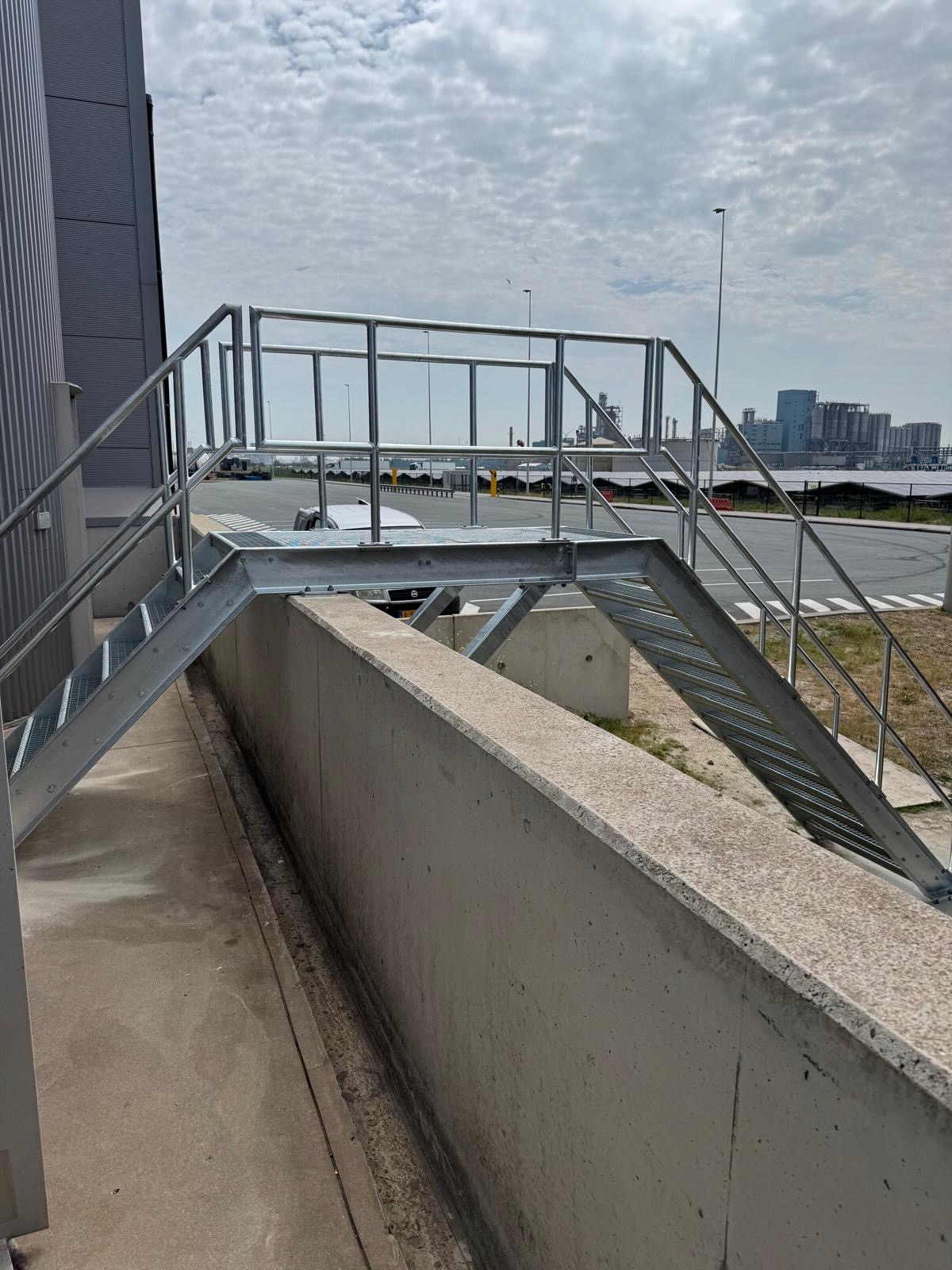 Trap met bordes over betonnen wand bij silopark